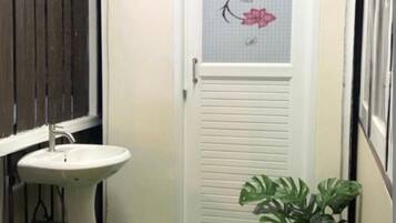 A small bathroom with a white door, a white sink, and a green artificial grass floor.