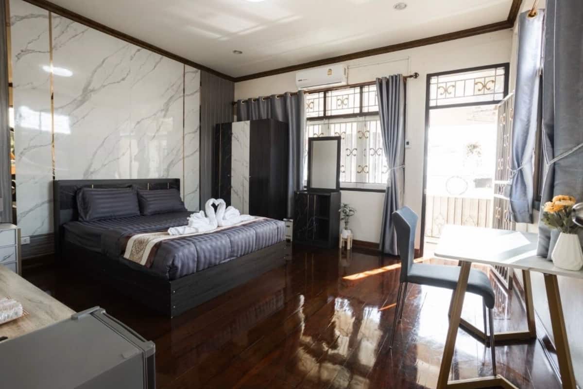 A modern bedroom with a large bed, a desk, and a vanity.