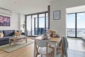 A modern living room with a dining area, large windows, and a city view.