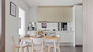 A modern kitchen with white cabinetry, a wooden dining table, and four chairs.