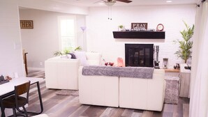 Una sala de estar moderna con un sofá blanco, una mesa de comedor con sillas y una chimenea.