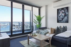 A modern living room with a large window, a sofa, a coffee table, and a painting of a lion.