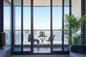 Un balcón con vistas a un paisaje urbano, una mesa con sillas y una planta en maceta.