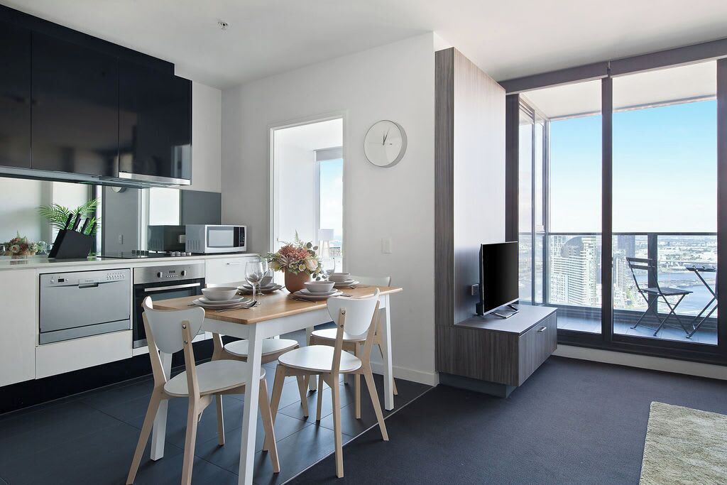 Eine moderne Küche mit Essbereich, einem Fernseher und einem Balkon mit Blick auf die Stadt.