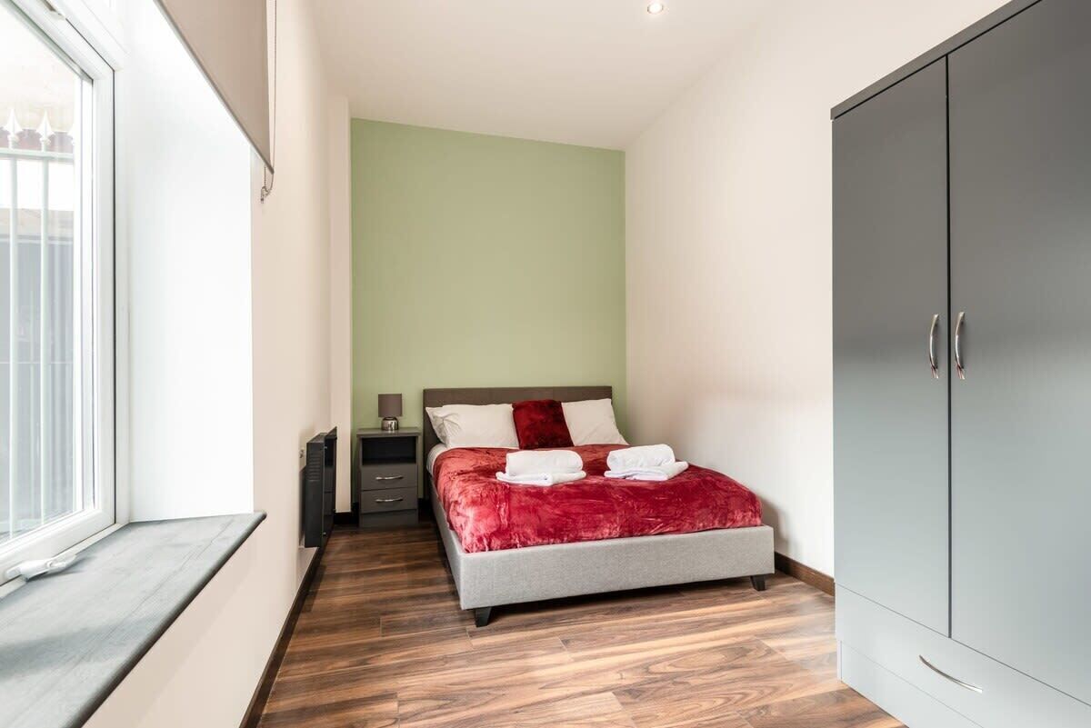 Ein Schlafzimmer mit Bett, Kleiderschrank, Nachttisch und Fenster.