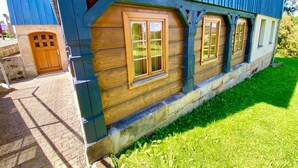 A traditional wooden house with a blue exterior, a stone foundation, and a wooden door.