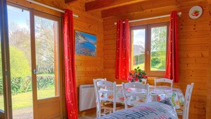 Un accogliente chalet in legno con zona pranzo, ampie finestre e un quadro appeso al muro.