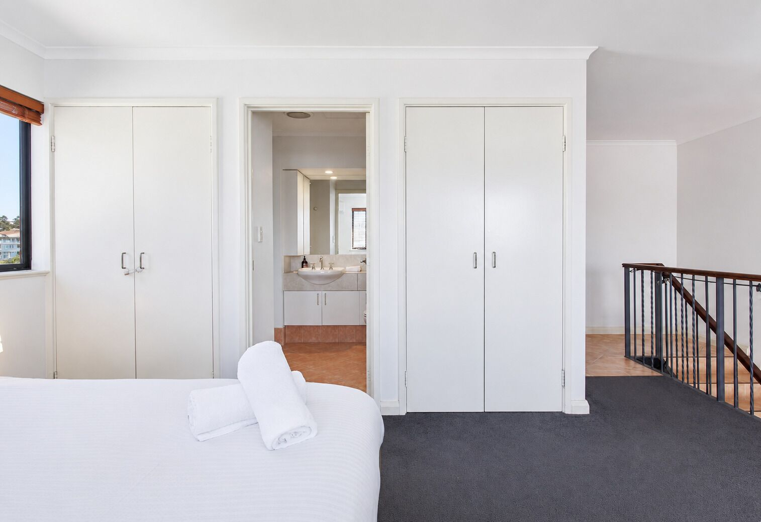 A hotel room with a bed, a bathroom with a sink, and a staircase.
