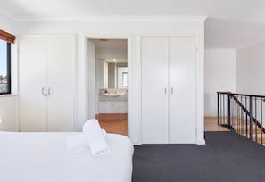 A hotel room with a bed, a bathroom with a sink, and a staircase.