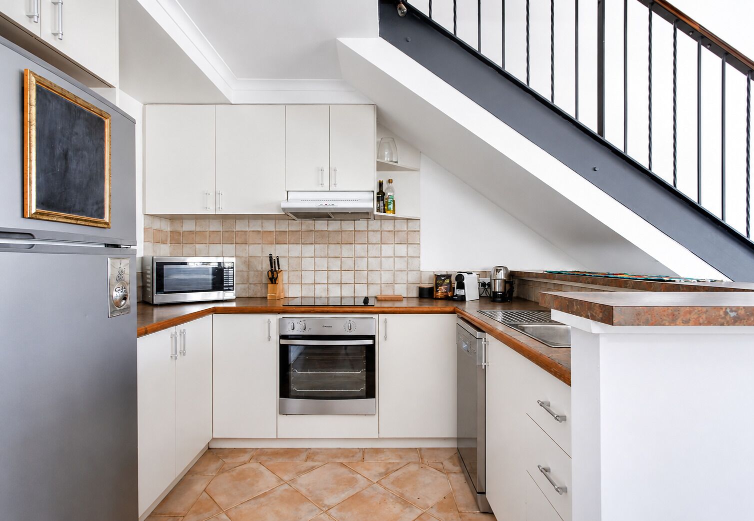 A compact kitchen with a built-in oven, microwave, and dishwasher.