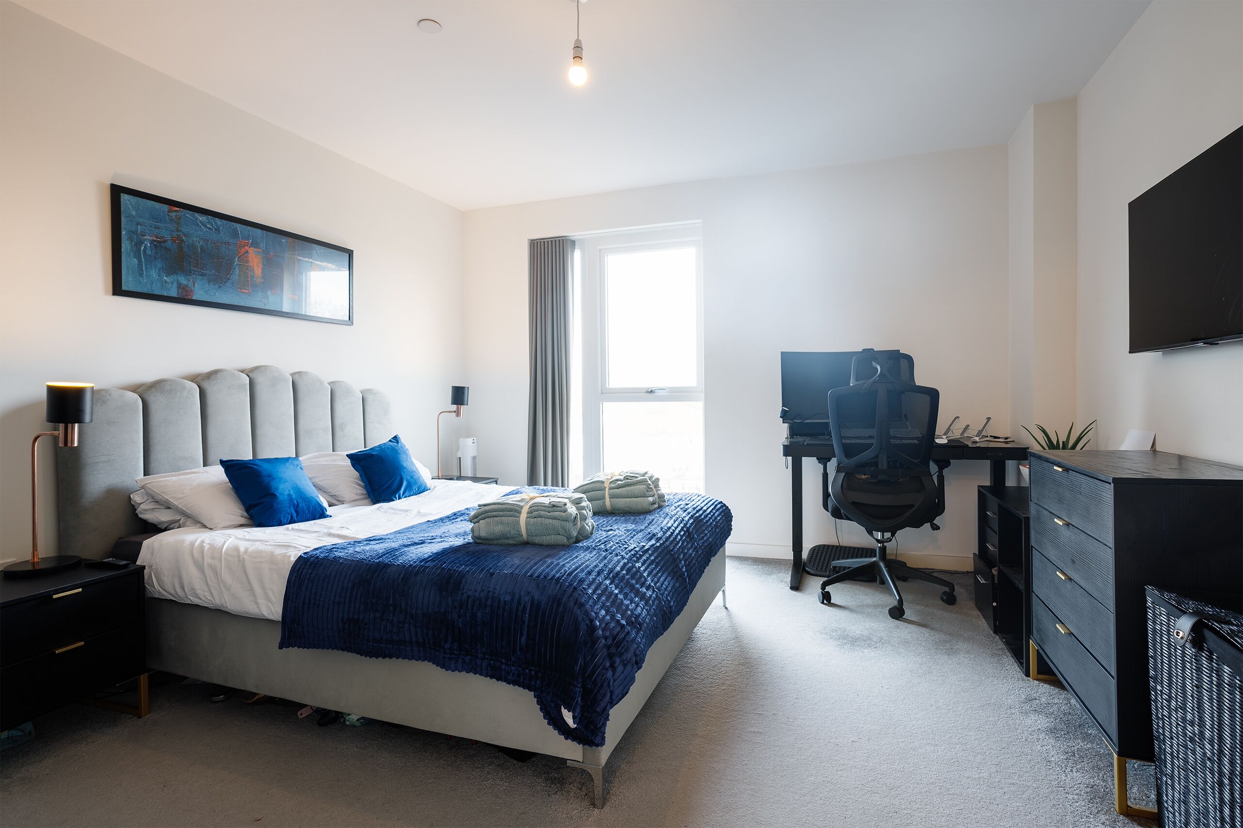 Une chambre à coucher moderne, avec un lit, un bureau et un téléviseur.