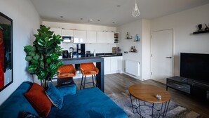 A modern living room with a blue sofa, a coffee table, and a TV. - Charming 1-bed Apartment in London (London)