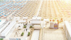 A beachside hotel with multiple beach umbrellas, sun loungers, and a designated area for beach activities. - Hotel Vela d'Oro (Rimini)