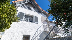 Un bâtiment blanc avec un toit recouvert de tuiles rouges, un balcon et un escalier.
