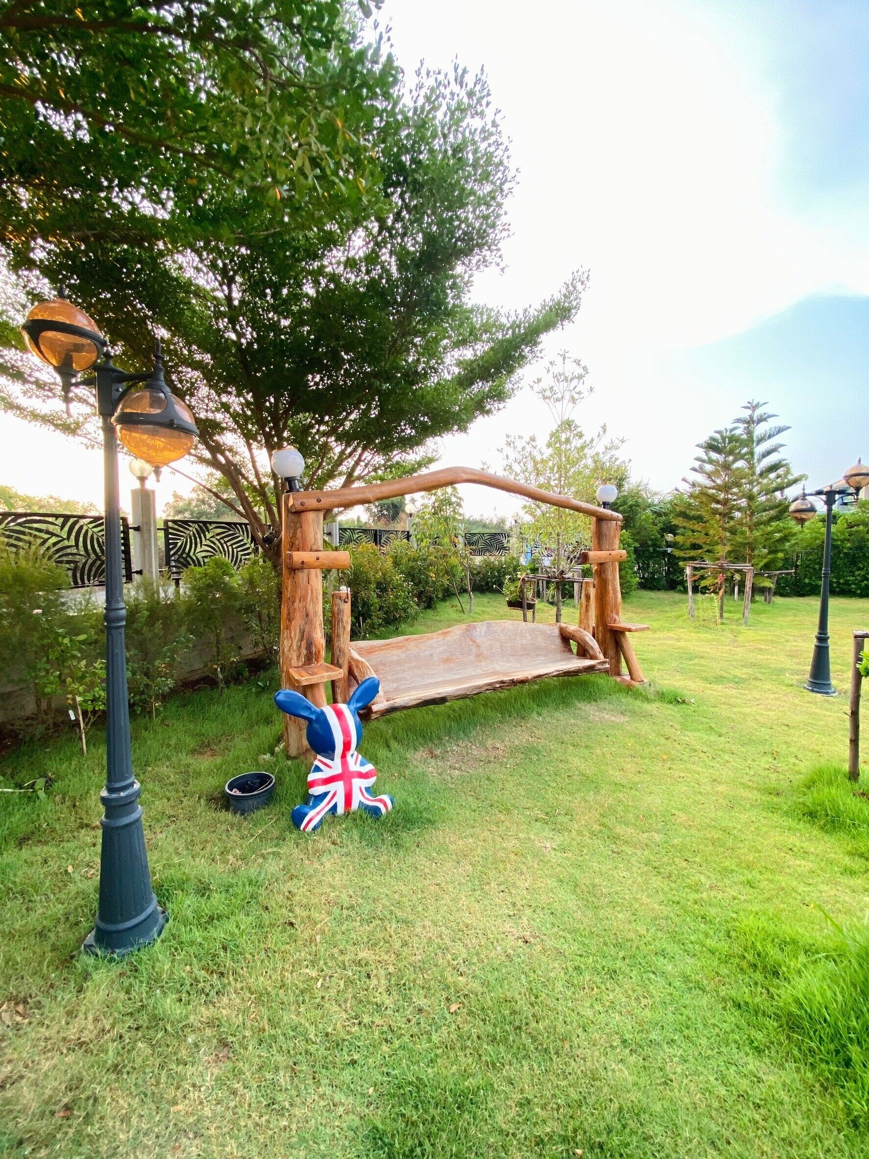A wooden swing set in a grassy area with a British flag and a lamp post nearby.