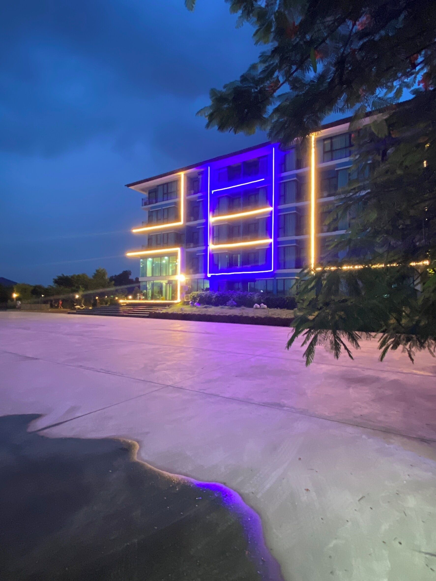 Un edificio moderno con fachada de vidrio y líneas de neón iluminadas.