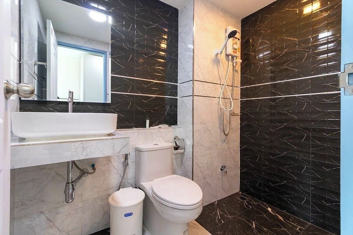 Un baño moderno con lavamanos, inodoro y ducha blancos.