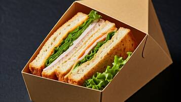 Un sándwich en una caja de cartón con lechuga.