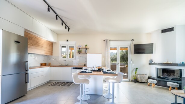 A modern kitchen with a central island, white bar stools, and a dining table. - Newly Built Home with Garden, 400m. to Beach (Kokkini Hani)