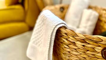 A woven basket with a white towel draped over it, placed on a wooden surface.