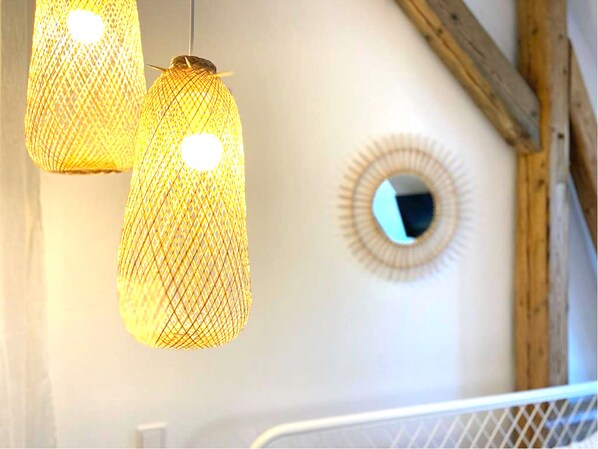 A room with a white wall, a circular mirror, and two hanging light fixtures.