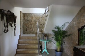Stairs lead to an upper level, flanked by a stone wall and a potted plant.