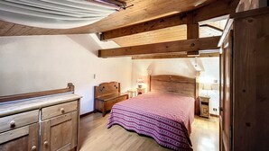 A wooden bedroom with a bed, a nightstand, a dresser, and a window with curtains. - Mezzanine studio in Combloux center with parking (Combloux)