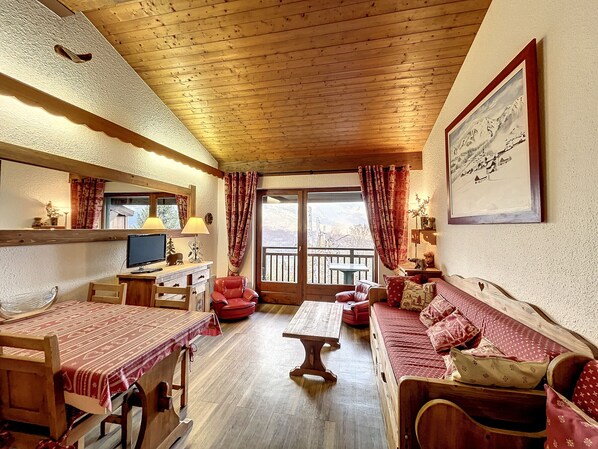 A cozy room with wooden furniture, a desk with a computer, a sofa, and a dining table. - Mezzanine studio in Combloux center with parking (Combloux)