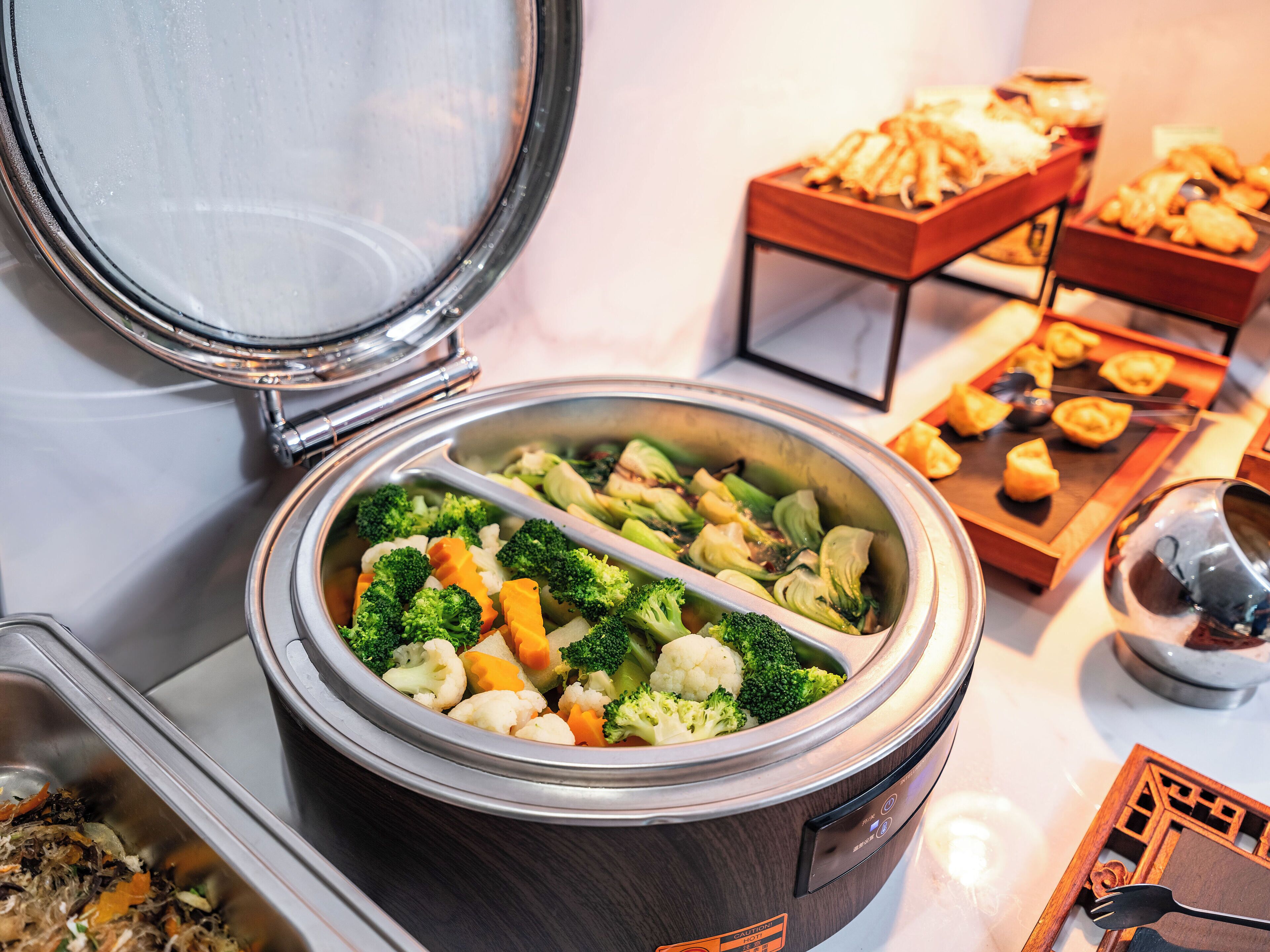 En buffé med ett stort utbud av grönsaker och en slow cooker (en typ av matlagningsapparat).