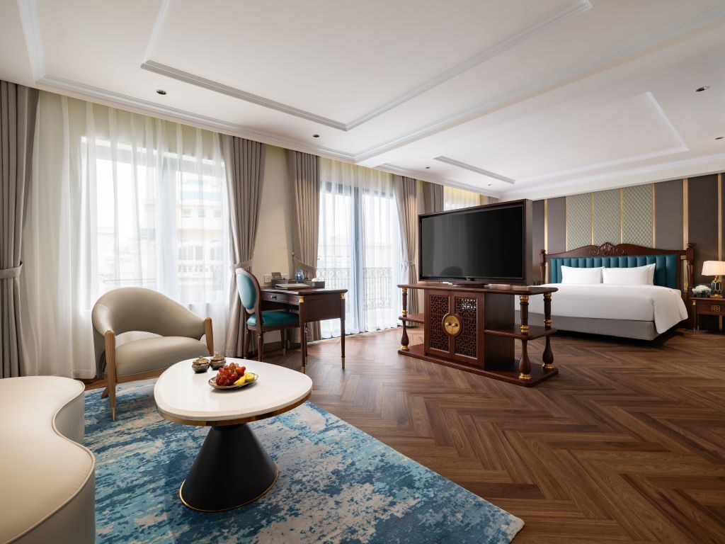 A hotel room with a bed, a TV, a desk, and a chair.