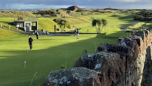 A golf course with a bunker, a flag, and a distant view of a city skyline. - Castleshaw Holiday Home (Castlerock)