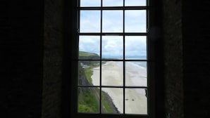 A window with a view of a beach and cliffs. - Castleshaw Holiday Home (Castlerock)