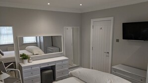A bedroom with a bed, a dresser, a mirror, a television, and a wardrobe. - Castleshaw Holiday Home (Castlerock)