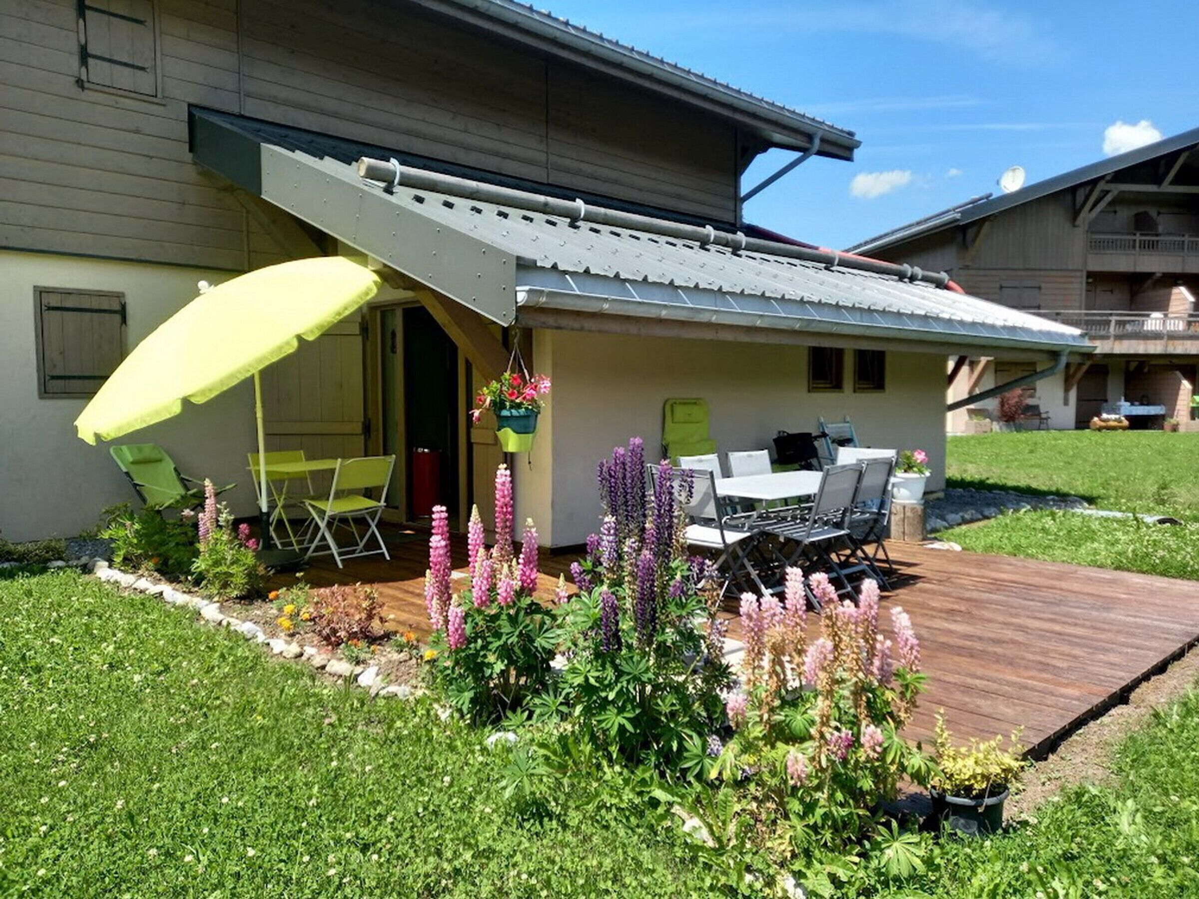 Uma casa com varanda, móveis de exterior e um cesto de flores pendurado.