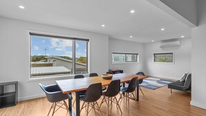 A modern meeting room with a large table, six chairs, and large windows offering a view of buildings and greenery. - Igneous Ridge - Calm and Quiet Retreat (Port Fairy)