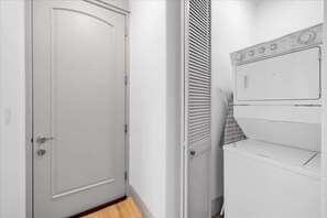 Una puerta blanca con manija de plata, una pared blanca y un electrodoméstico blanco con panel de control.