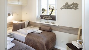 Een slaapkamer met twee bedden, een raam met uitzicht en een decoratief kunstwerk.