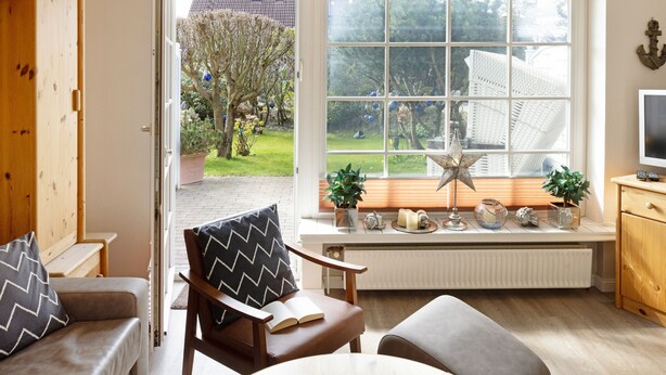 Een gezellige woonkamer met een groot raam, een houten kast, een comfortabele bank en een leeshoek.