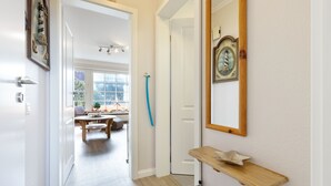 Een gang met een houten console tafel, een spiegel en een deur naar een eethoek.
