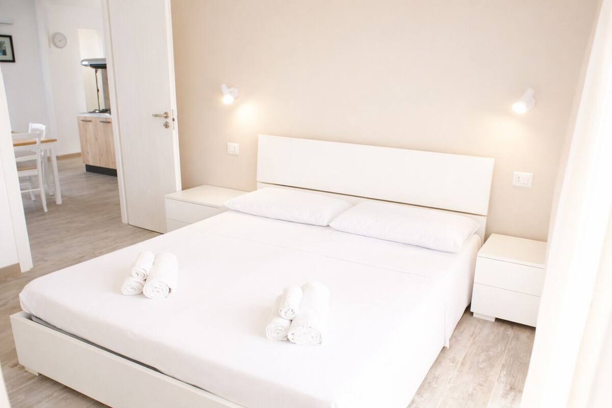 A modern bedroom with a large bed, white linens, and bedside lamps.