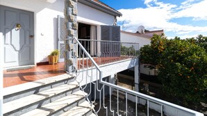 Un bâtiment blanc doté d’un balcon, d’une porte et d’une fenêtre.