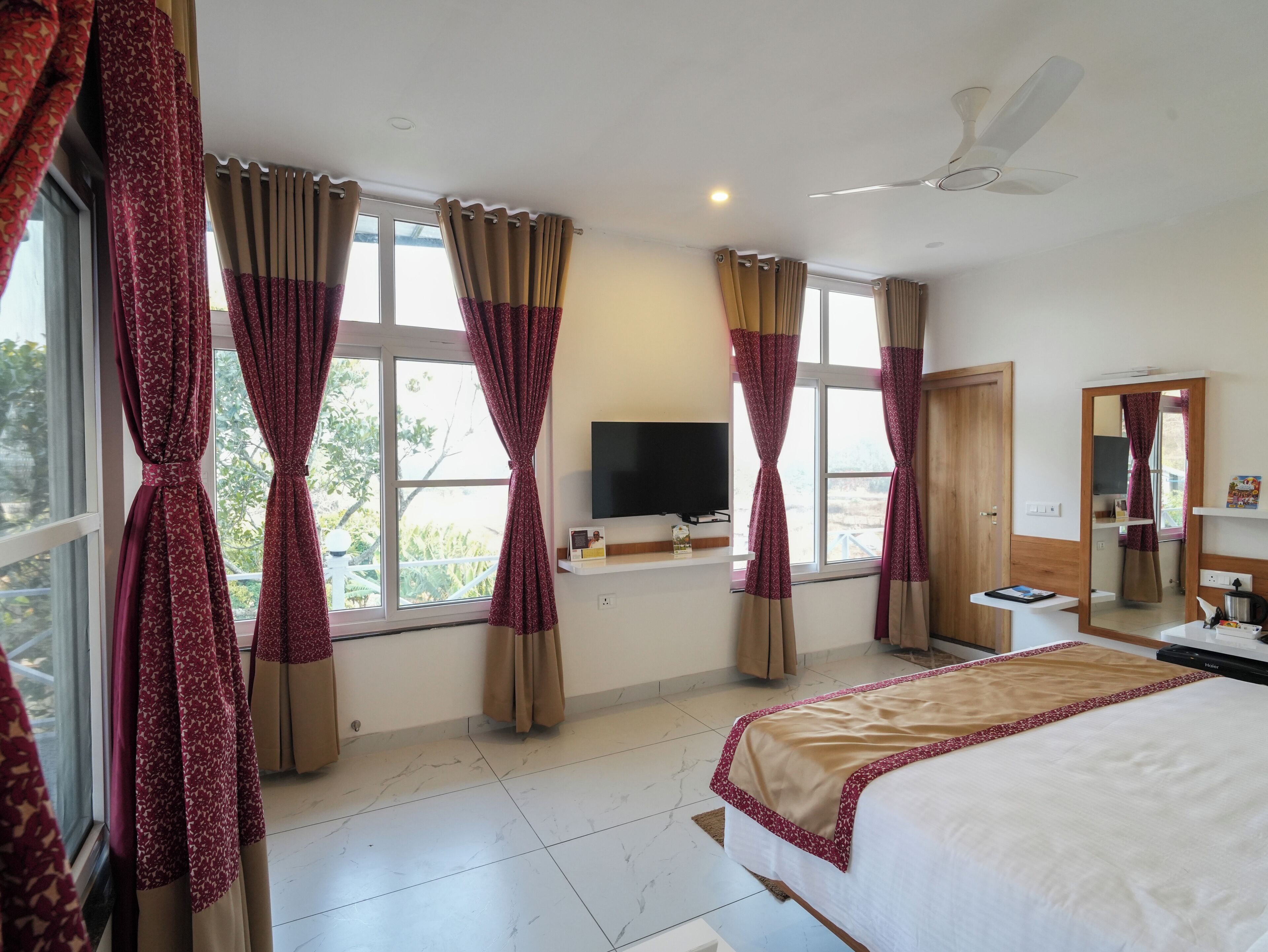 A hotel room with a bed, a TV, a desk, and a ceiling fan.