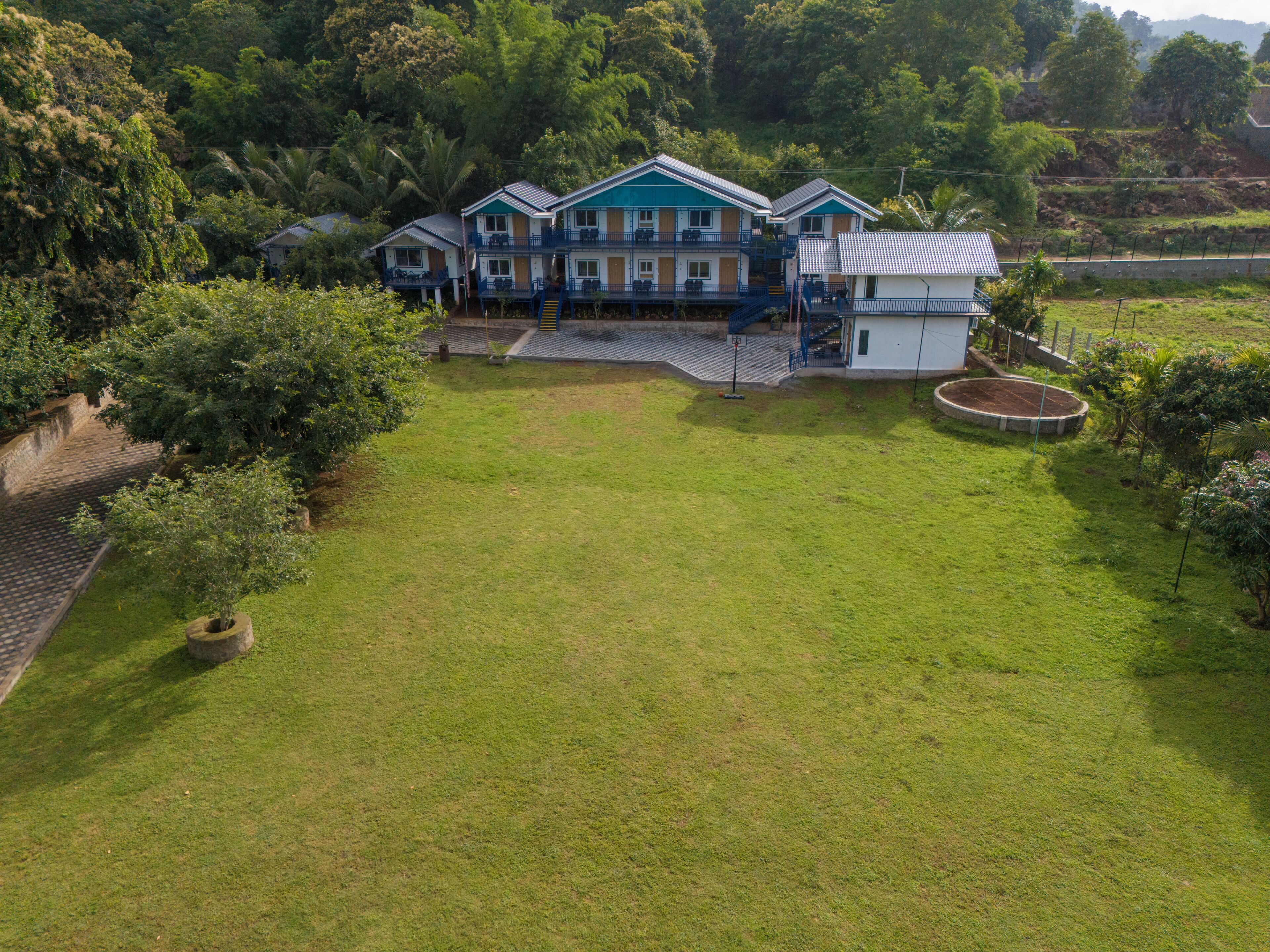 A large house with a spacious lawn, a pool, and a staircase leading to a balcony.