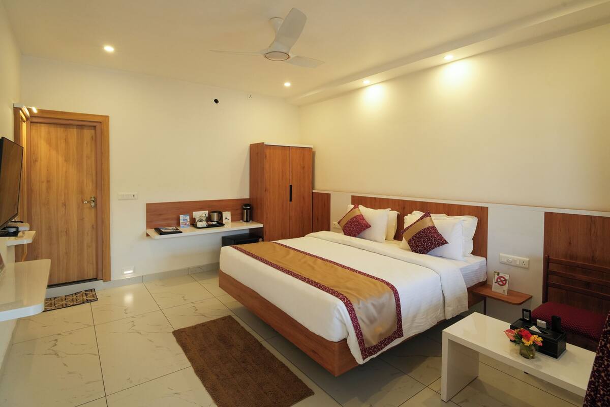 Una habitación de hotel con cama, mesita de noche, armario y ventilador de techo.