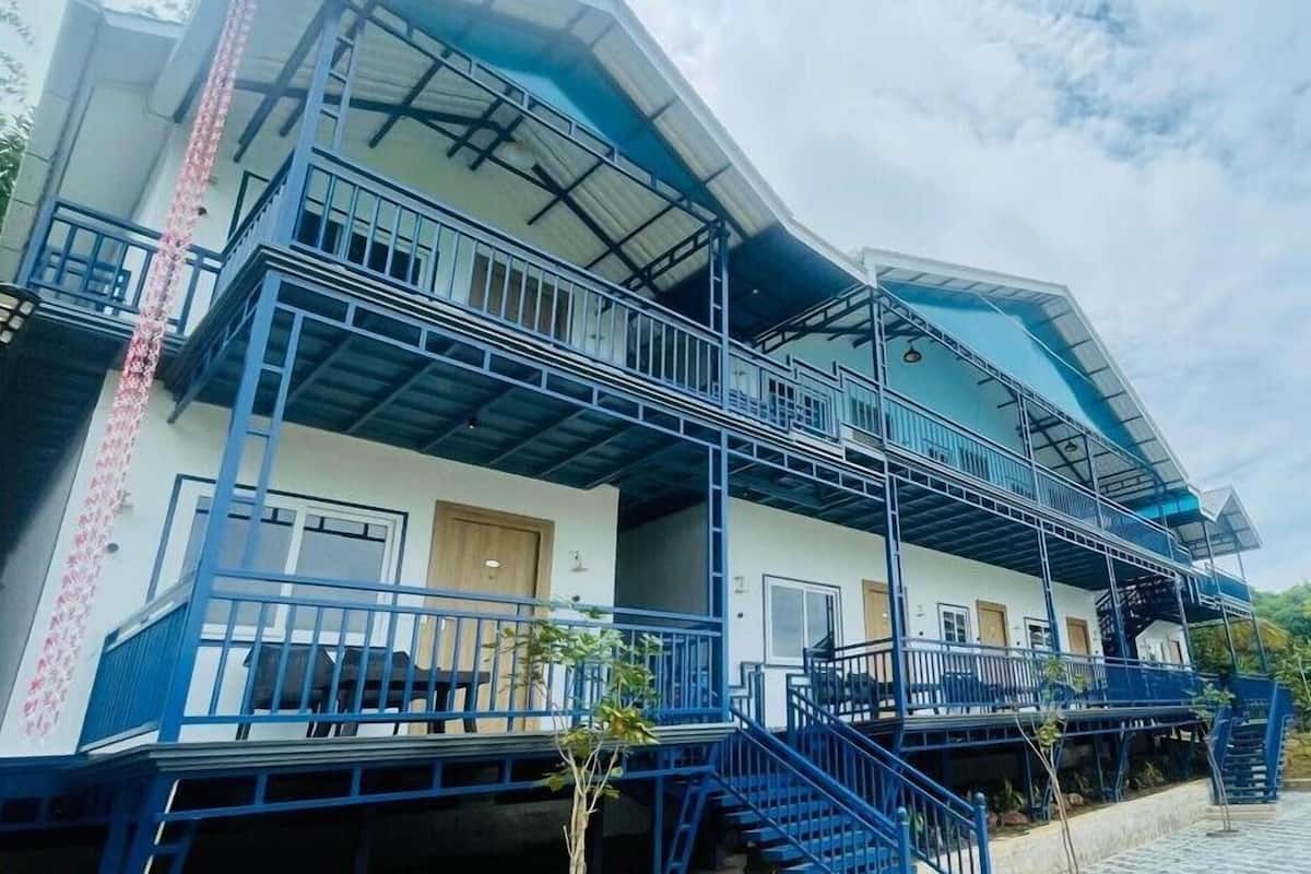 Un edificio de varios pisos con fachada azul, múltiples balcones y una escalera que conduce a los niveles superiores.