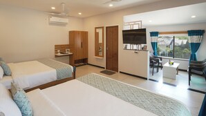 Habitación de hotel con dos camas, televisión, escritorio y ventana con cortinas.