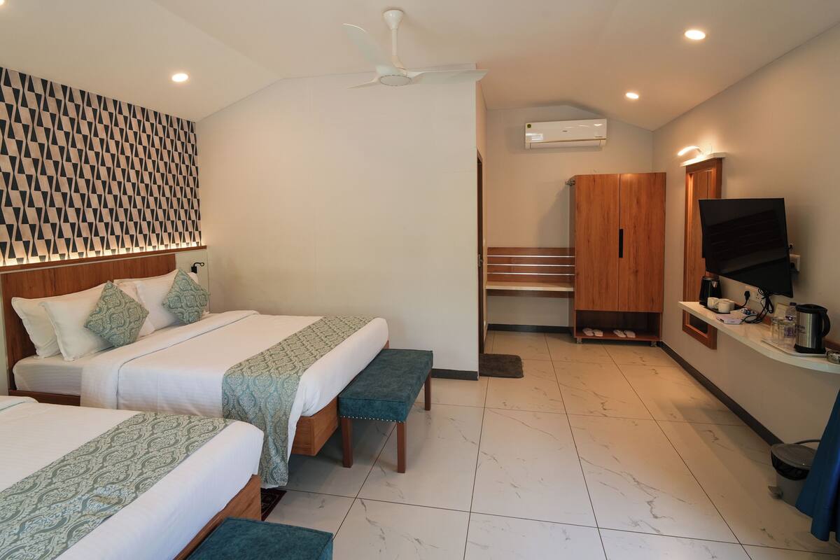 Habitación de hotel con dos camas, un banco, un televisor, un armario y un baño.