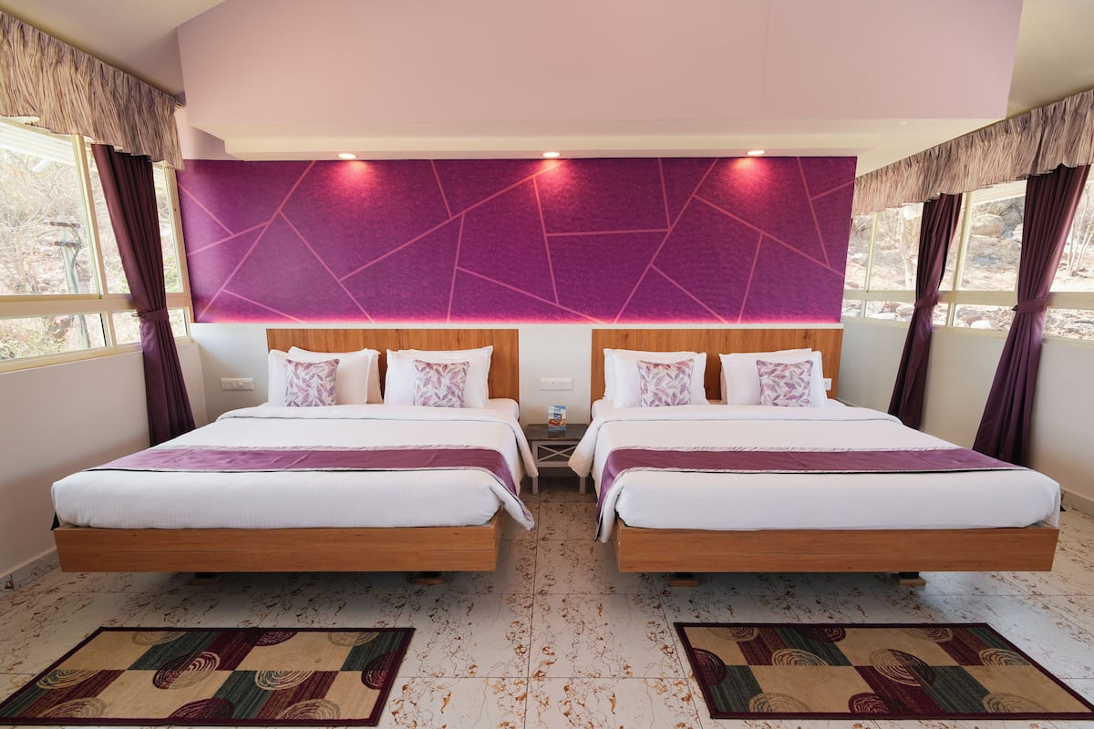 Habitación doble con dos camas, una pared de acento morada y piso estampado.