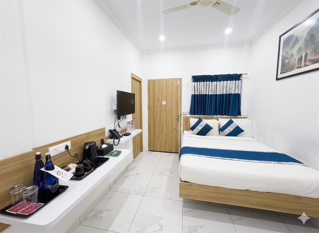Hotelkamer met een bed, een bureau met een flatscreen televisie, een koffiezetapparaat en een raam met gordijnen.