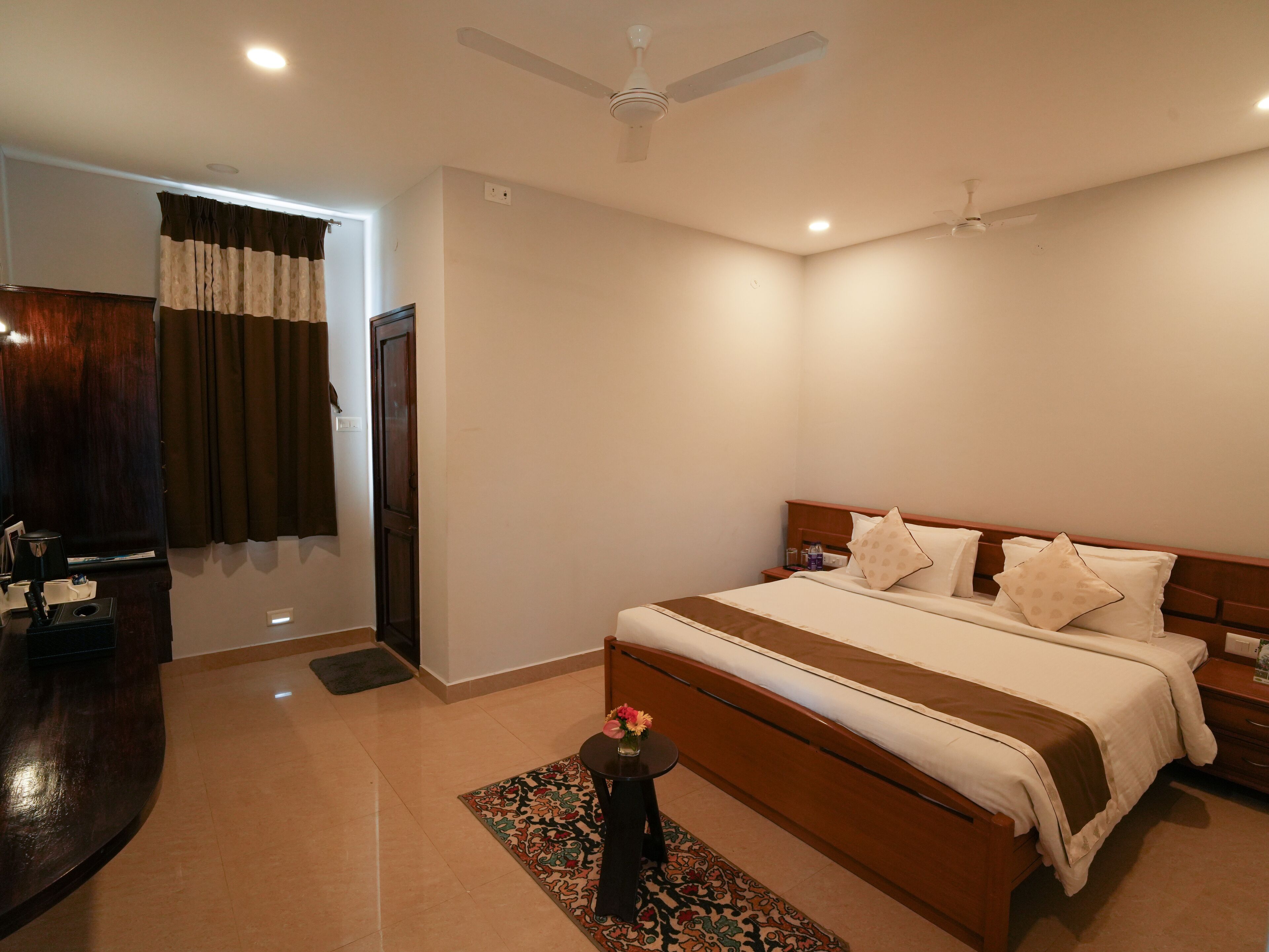 A hotel room with a bed, bedside tables, a desk, and a ceiling fan.